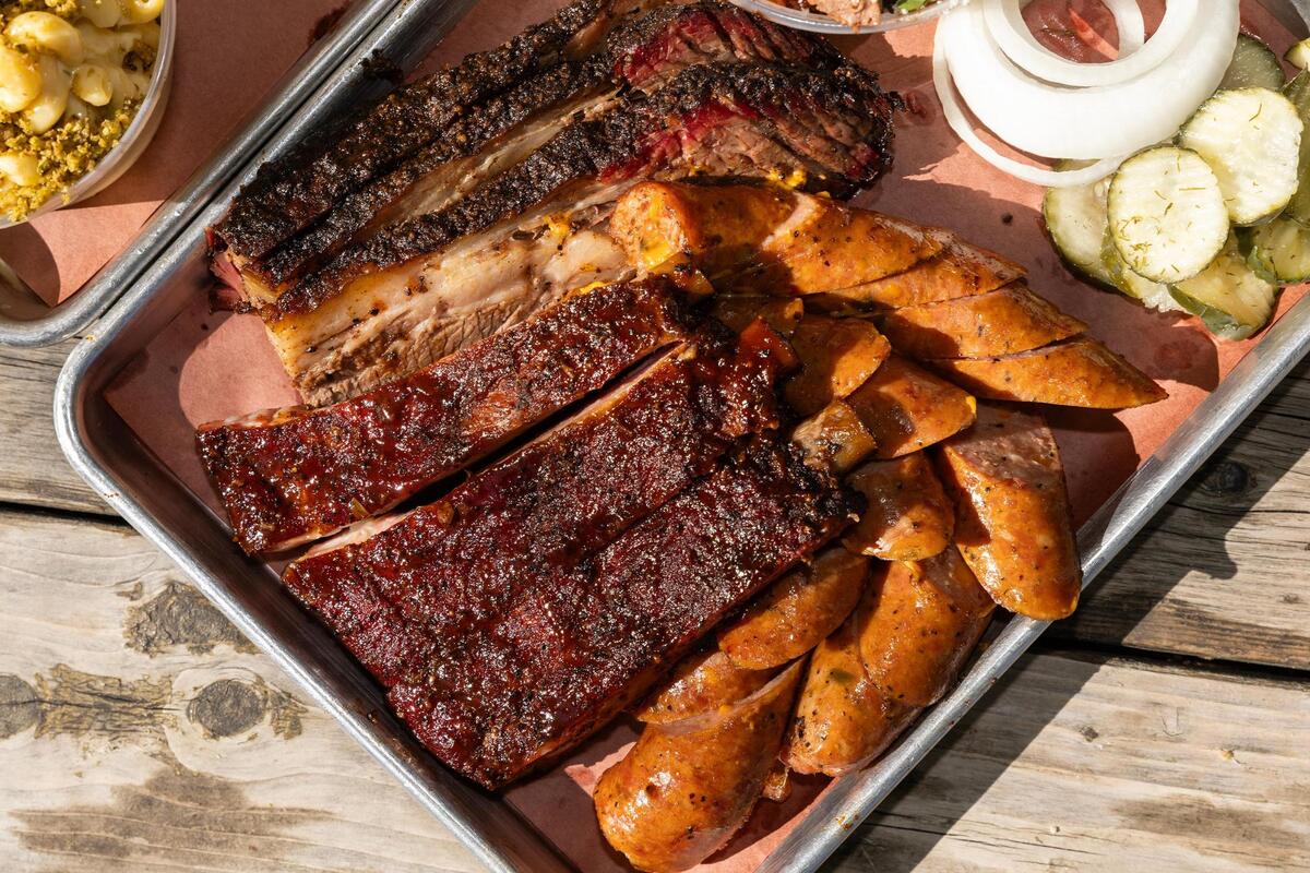 A platter with brisket, pork spare ribs, jalapeño cheese sausage, and a brisket eloté cup are paired with sides of collard greens, spicy smoked Mac & Cheese, banana pudding, and sliced bread at Panther City BBQ in Fort Worth. Panther City BBQ landed a spot on the Michelin recommended list making it one of the three restaurants Fort Worth to make the prestigious catalog.